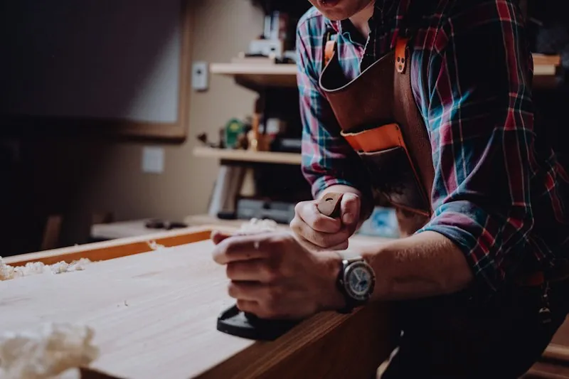 Menuisier au rabot dans son atelier