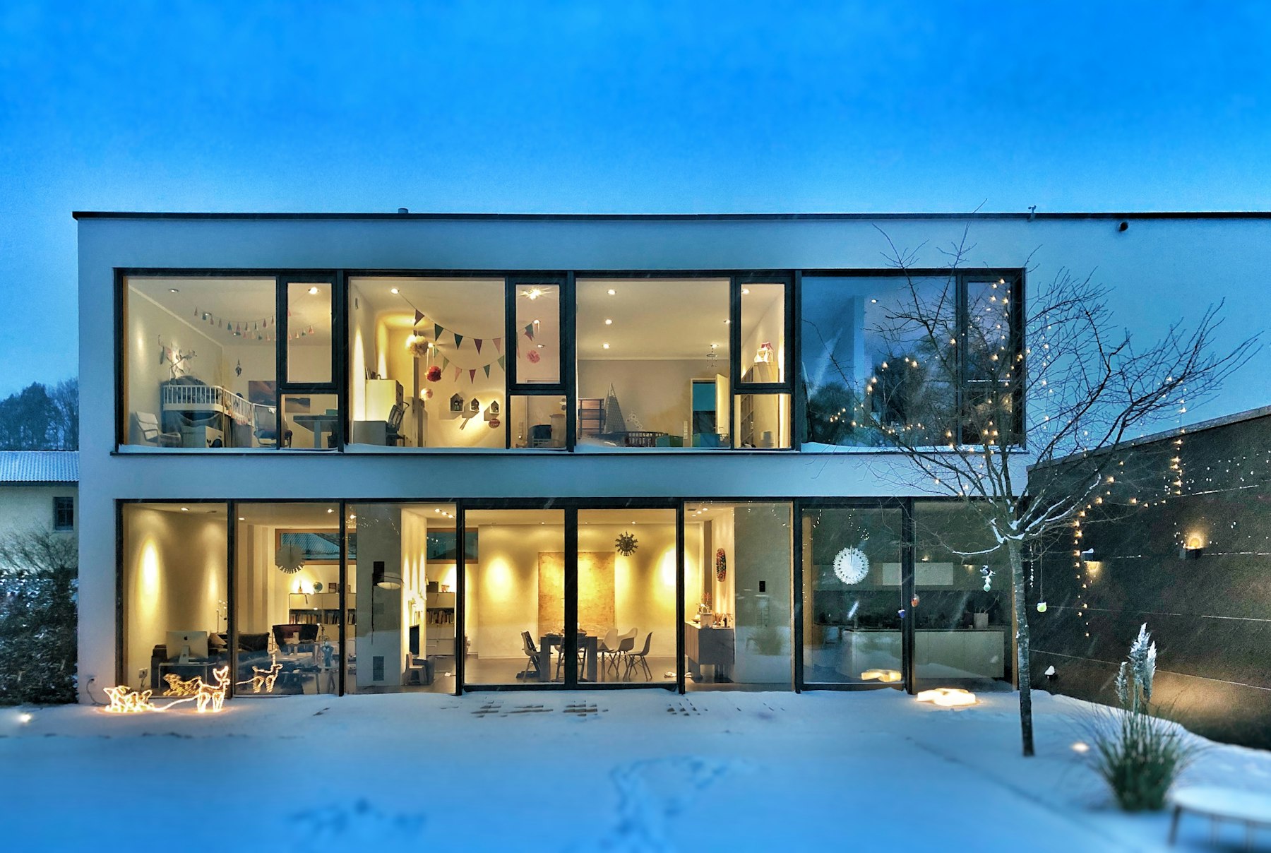 Maison contemporaine aux grandes baies vitrées, à la tombée du jour